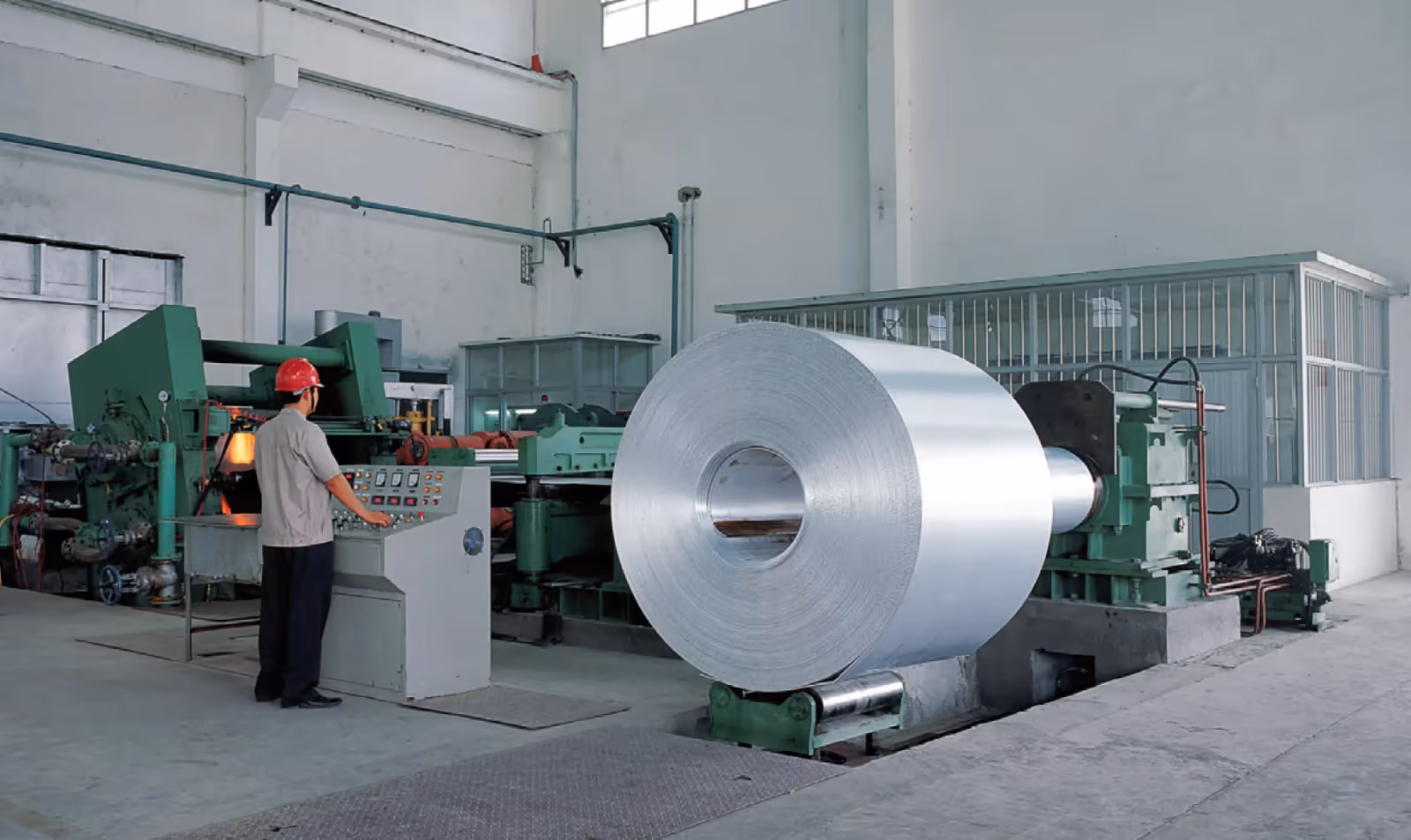 An operator moving a finished aluminum coil on the shop floor