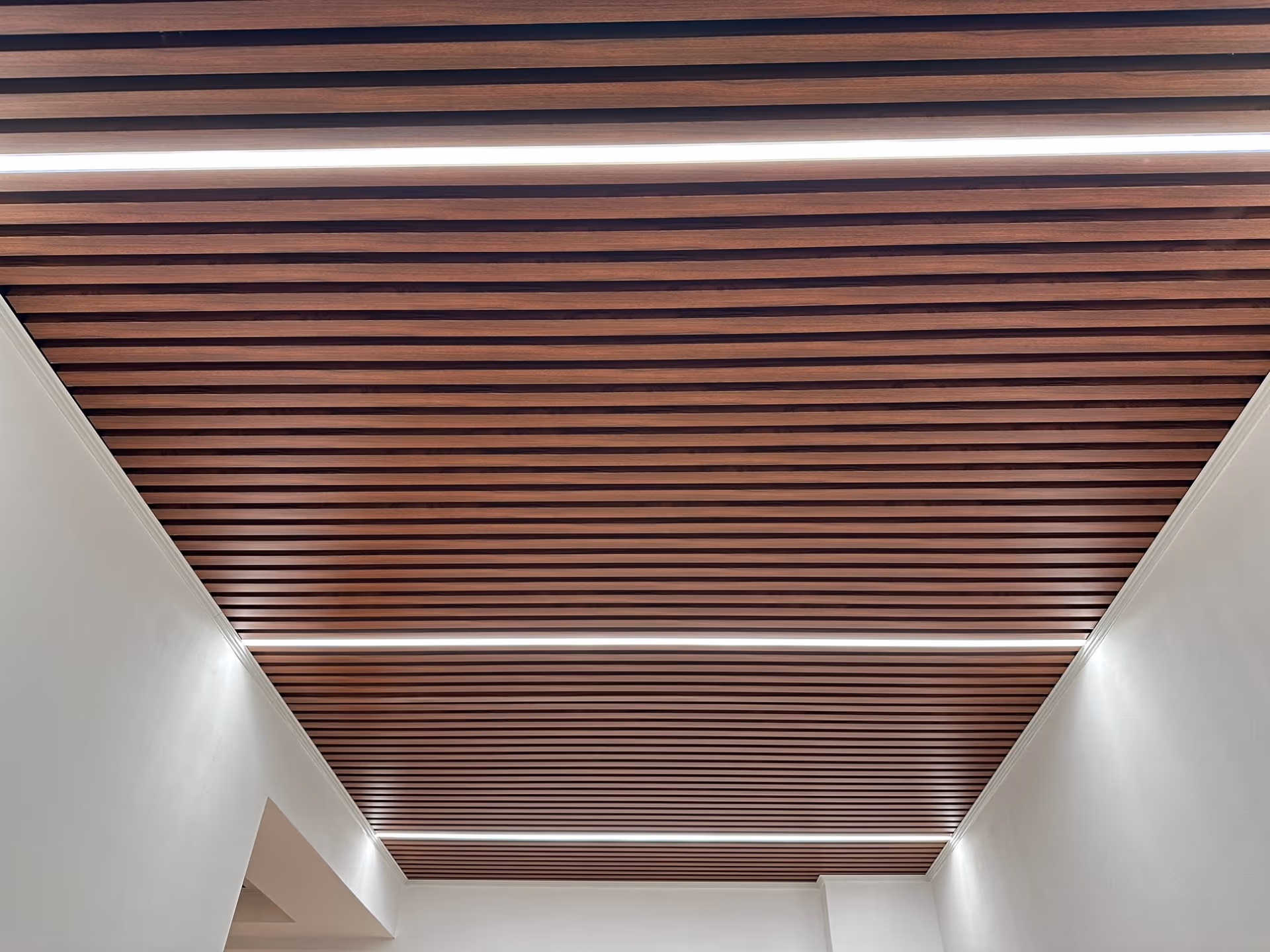 Wood grain baffle ceiling running along a lit corridor