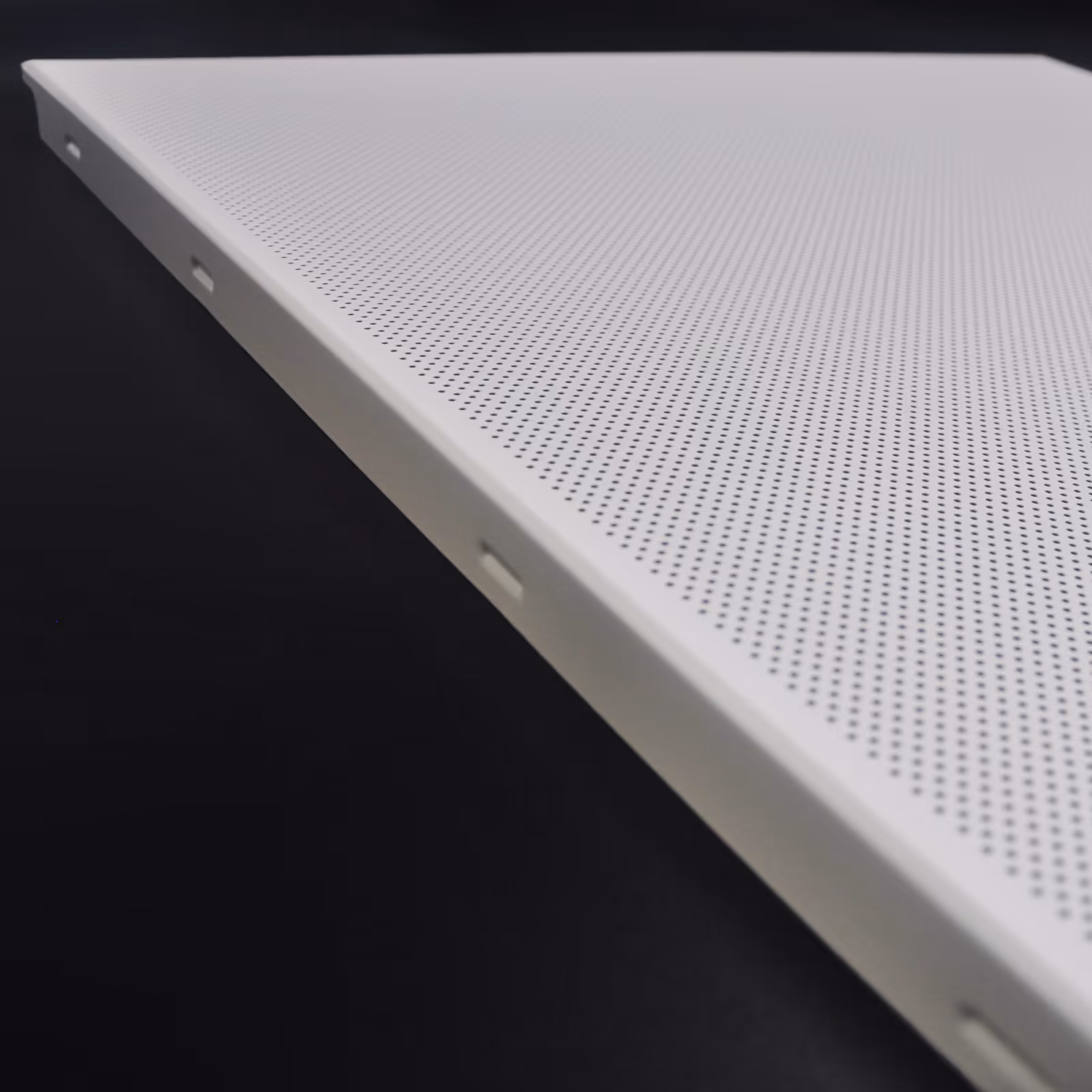 Edge profile of a clip-in ceiling panel against a dark ground