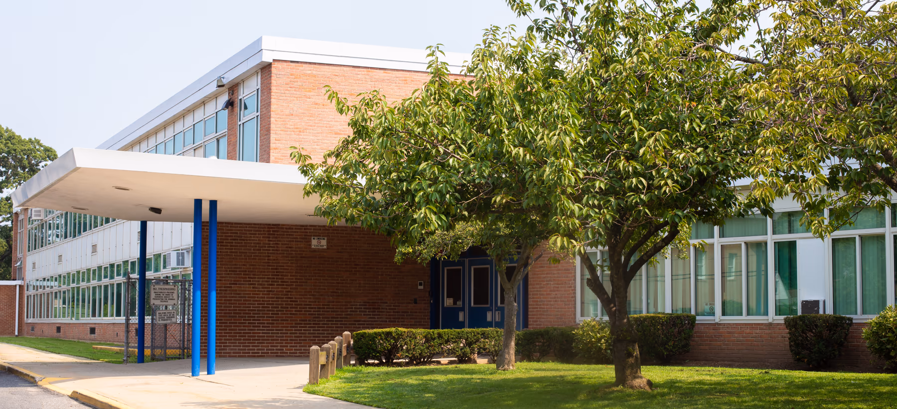 Brick school building with a covered entrance canopy and classroom windows