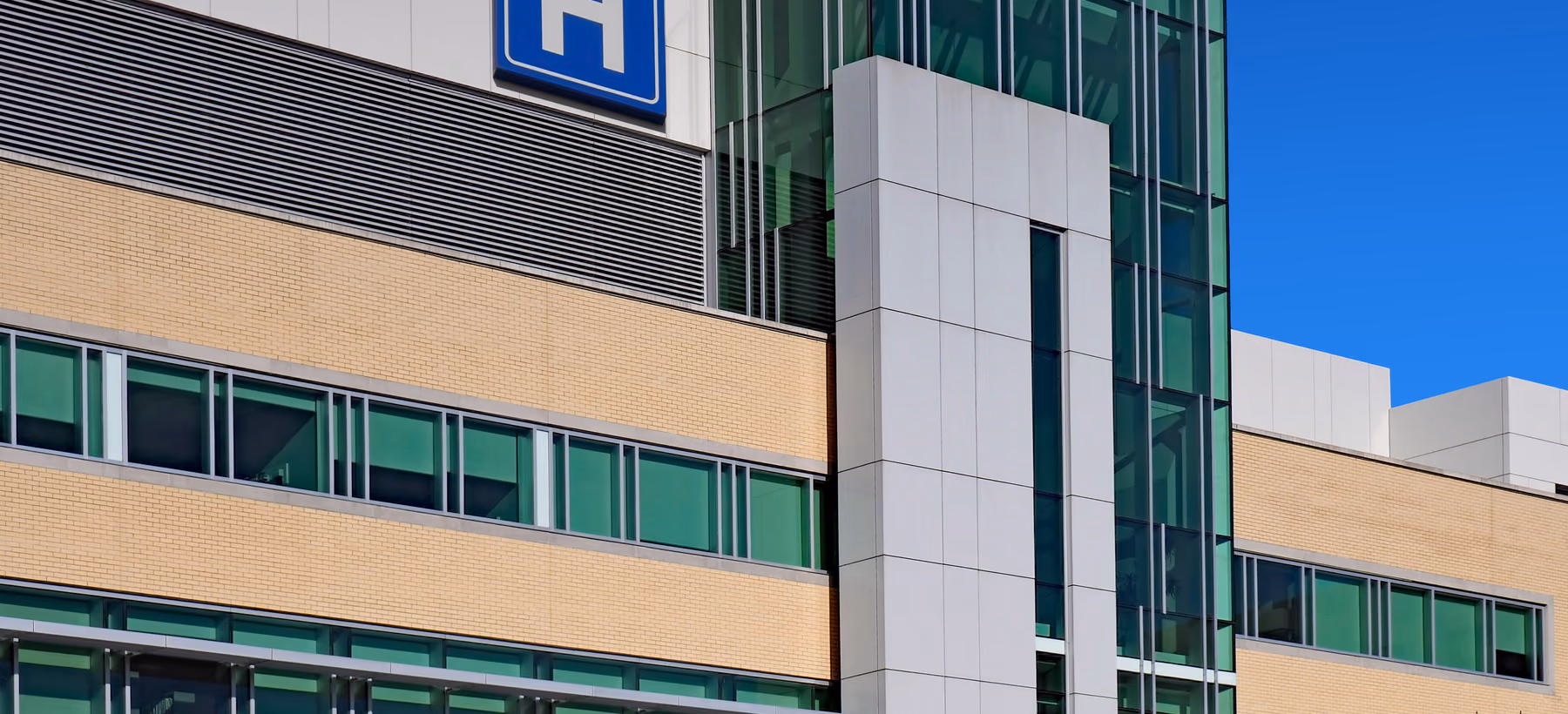 Exterior of a modern hospital building with a hospital sign on the facade